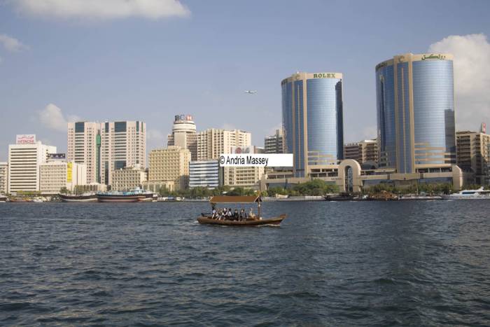 Dubai United Arab Emirates View across Dubai Creek to the iconic buildings of Deira City with an abra taking tourists on a tour of the waterway
