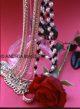 Red rose with draped jewellery on red background